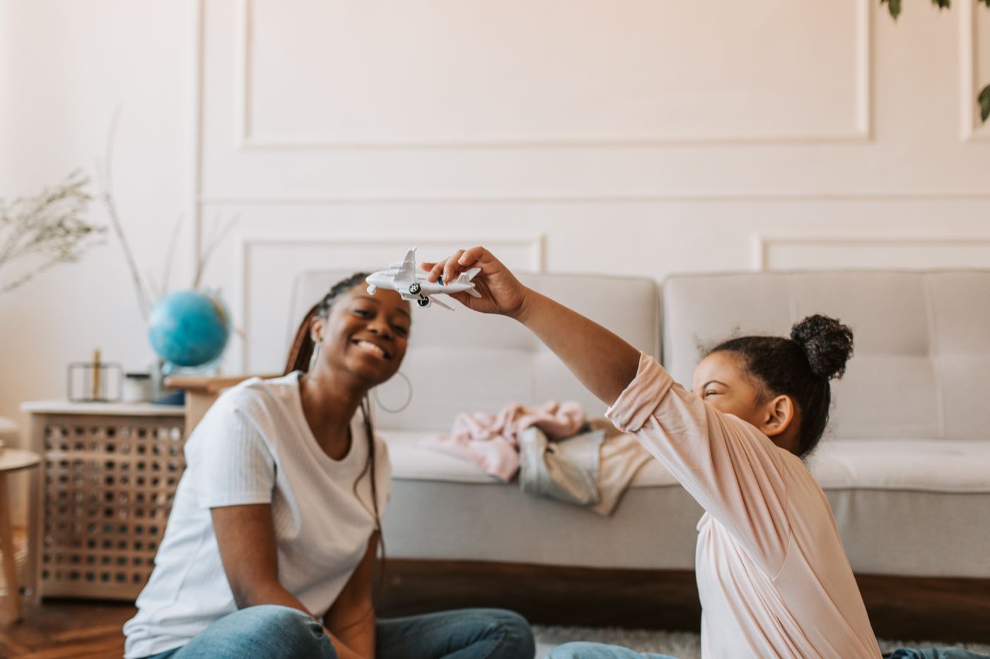 A mother and daughter playing with a toy airplane together on the floor