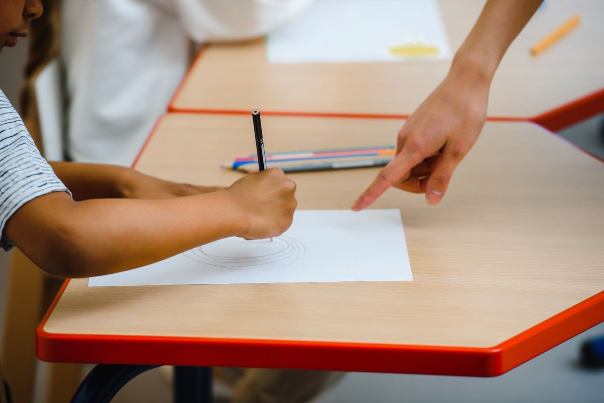 A child practicing drawing with an adult’s guidance